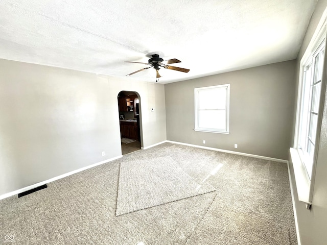 empty room with ceiling fan, carpet flooring, and a textured ceiling