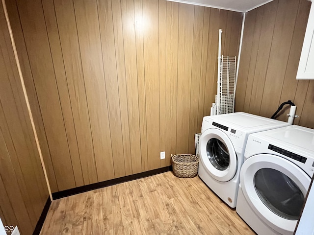 washroom with wooden walls, washer and clothes dryer, and light hardwood / wood-style floors