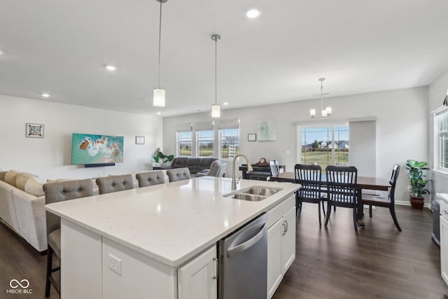 kitchen with decorative light fixtures, white cabinetry, dishwasher, sink, and a kitchen island with sink