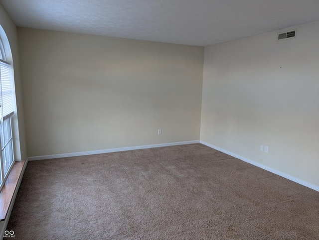 carpeted empty room with a textured ceiling