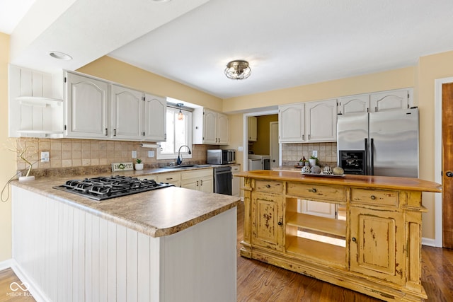 956 Dorchester Dr, Noblesville, IN 46062 - kitchen featuring open shelves, appliances with stainless steel finishes, a sink, a peninsula, and washer and clothes dryer