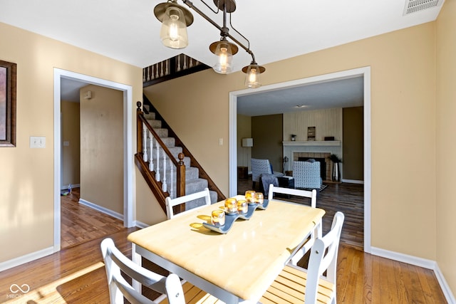 956 Dorchester Dr, Noblesville, IN 46062 - dining space with a fireplace, wood finished floors, baseboards, and stairs