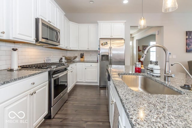 kitchen with pendant lighting, white cabinetry, sink, backsplash, and stainless steel appliances