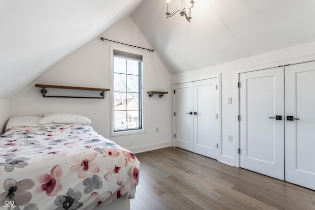 bedroom featuring two closets, light hardwood / wood-style flooring, and vaulted ceiling