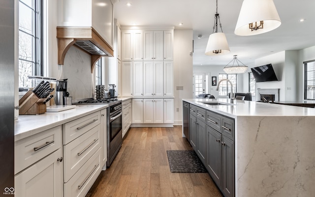 kitchen featuring sink, appliances with stainless steel finishes, pendant lighting, light hardwood / wood-style floors, and white cabinets