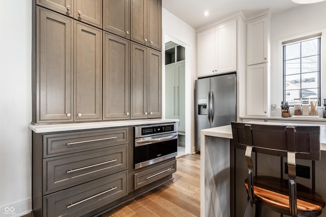 kitchen with white cabinetry, stainless steel appliances, light hardwood / wood-style floors, and gray cabinetry