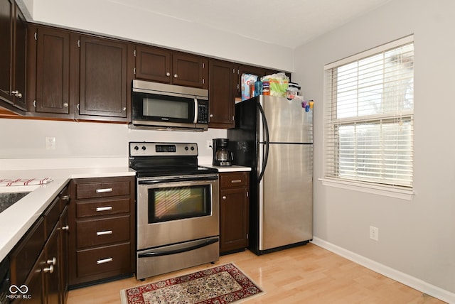 kitchen featuring dark brown cabinetry, stainless steel appliances, and light hardwood / wood-style floors