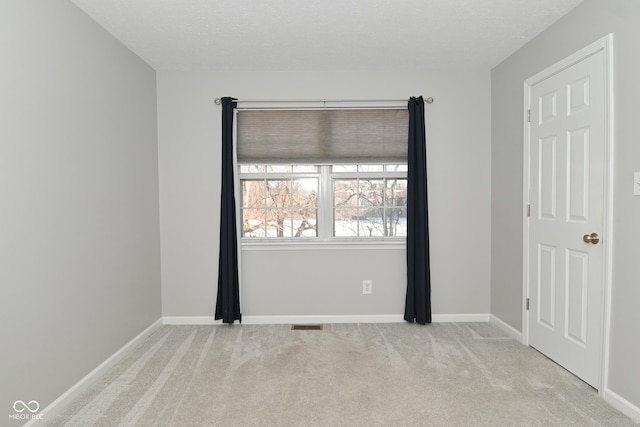 empty room with light colored carpet and a textured ceiling