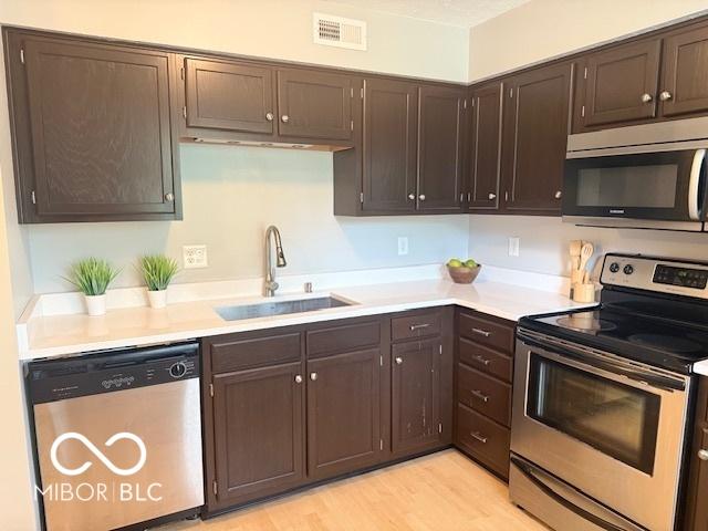 6639 N College Ave, Indianapolis, IN 46220 - kitchen featuring stainless steel appliances, a sink, light countertops, and light wood-type flooring