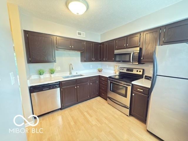 6639 N College Ave, Indianapolis, IN 46220 - kitchen featuring stainless steel appliances, a sink, light wood-type flooring, dark brown cabinets, and light countertops