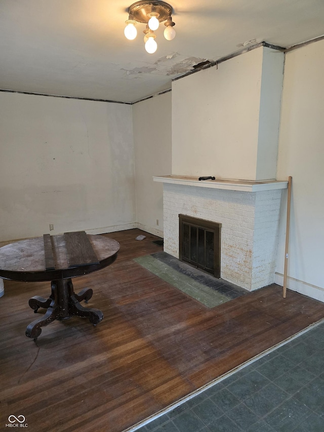 unfurnished living room with dark wood-type flooring and a brick fireplace