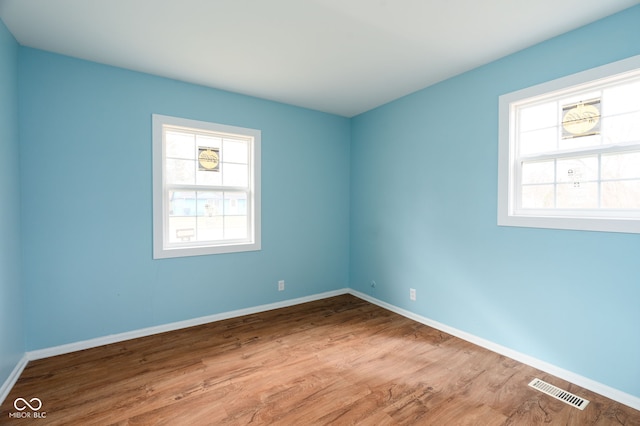 spare room featuring hardwood / wood-style flooring and a healthy amount of sunlight