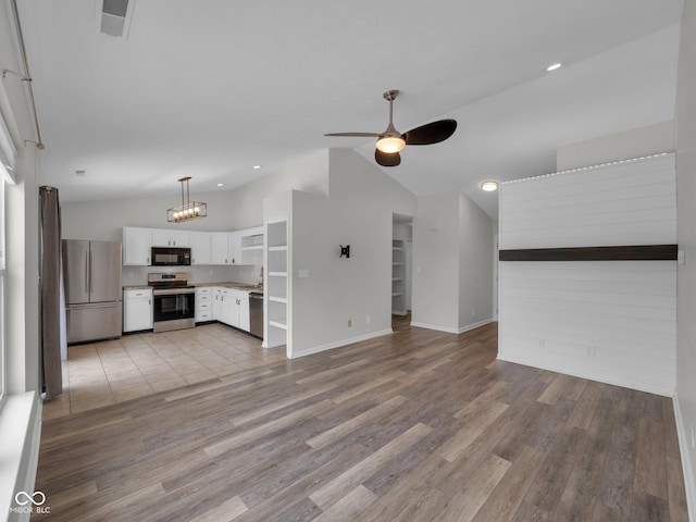 unfurnished living room with ceiling fan, vaulted ceiling, and light hardwood / wood-style flooring