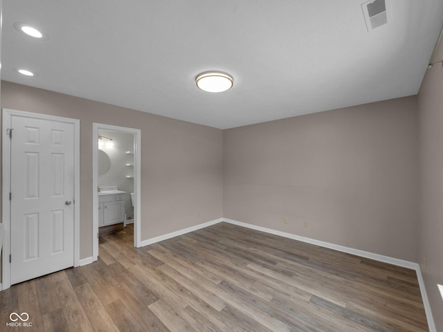 unfurnished bedroom with ensuite bath and light hardwood / wood-style floors