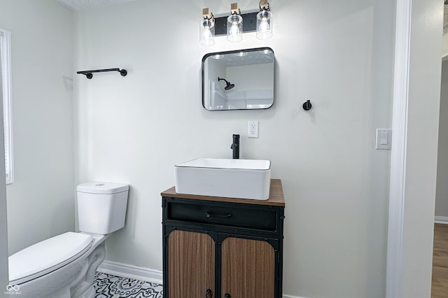 bathroom with toilet, vanity, and baseboards