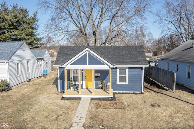 bungalow featuring roof with shingles, fence, a front lawn, and central air condition unit