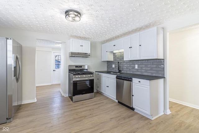 kitchen with tasteful backsplash, sink, white cabinets, light hardwood / wood-style floors, and stainless steel appliances