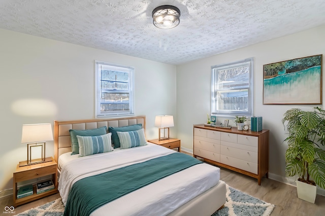 bedroom with light wood finished floors, multiple windows, and a textured ceiling