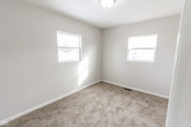 unfurnished room with light colored carpet and a wealth of natural light