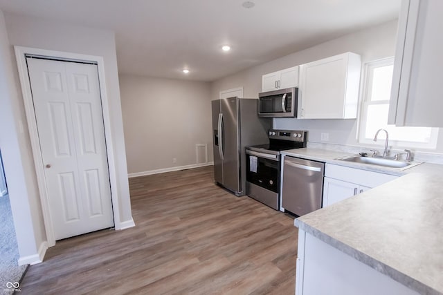 kitchen featuring appliances with stainless steel finishes, light hardwood / wood-style floors, sink, and white cabinets