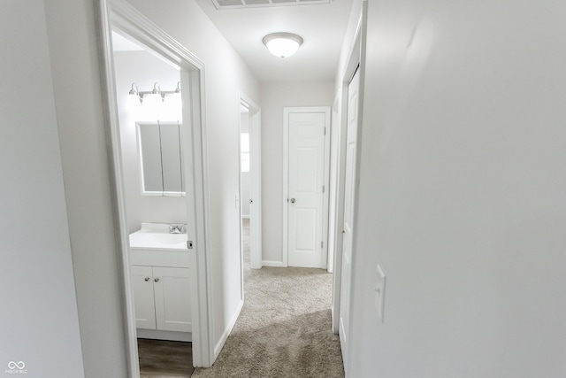 corridor with sink and carpet floors