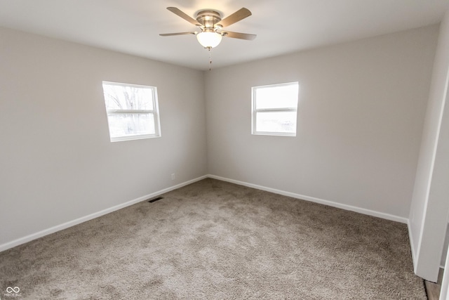 carpeted spare room with a wealth of natural light and ceiling fan