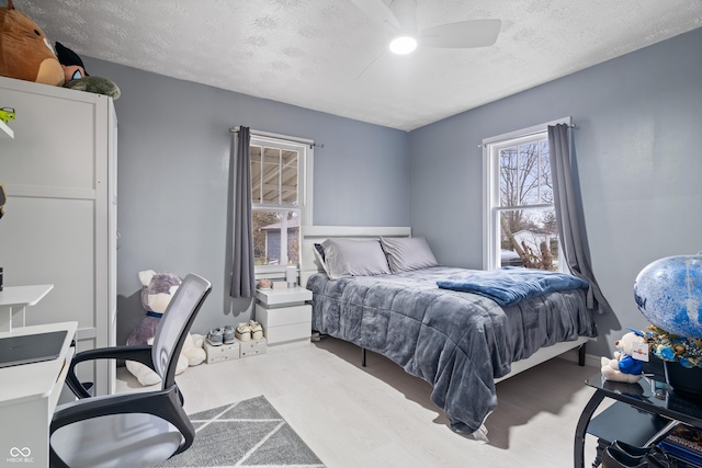 bedroom featuring ceiling fan, hardwood / wood-style flooring, and a textured ceiling