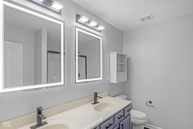 bathroom with vanity, a textured ceiling, and toilet