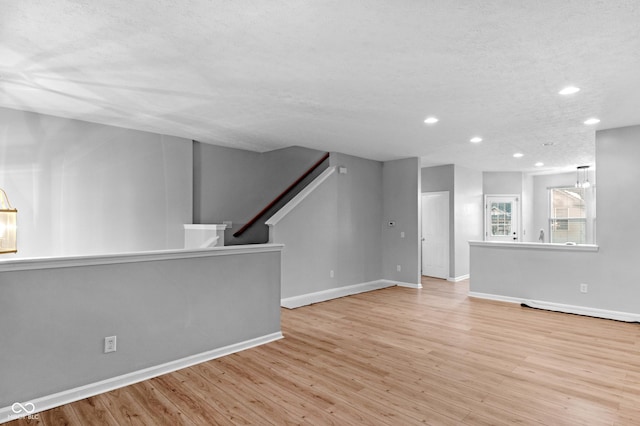 unfurnished living room featuring a textured ceiling and light wood-type flooring