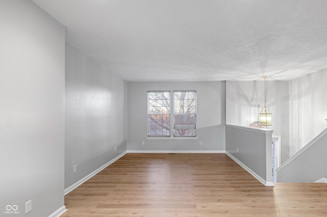 empty room with a textured ceiling and light wood-type flooring