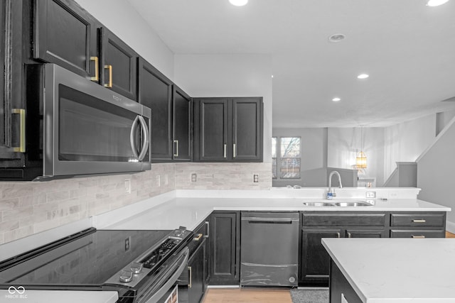 kitchen featuring tasteful backsplash, sink, kitchen peninsula, stainless steel appliances, and light hardwood / wood-style flooring