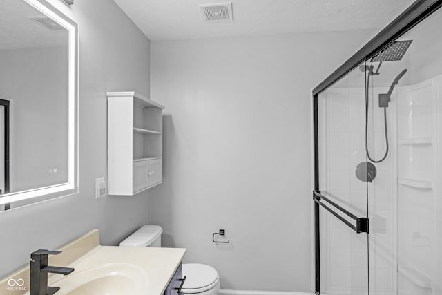 bathroom with vanity, a textured ceiling, toilet, and walk in shower