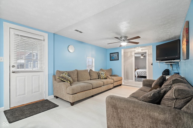 living room featuring ceiling fan, plenty of natural light, and a textured ceiling