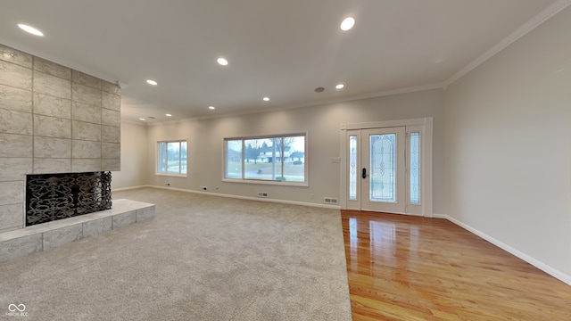 unfurnished living room featuring light carpet, crown molding, and a tile fireplace