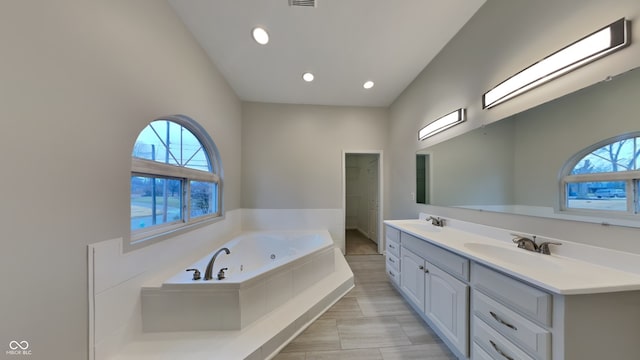 bathroom with vanity, tiled tub, and a wealth of natural light