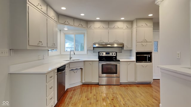 kitchen with appliances with stainless steel finishes, light hardwood / wood-style floors, sink, and white cabinets