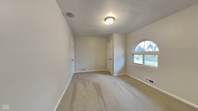 unfurnished room with light colored carpet and a textured ceiling