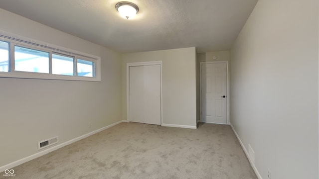 unfurnished bedroom with light colored carpet and a closet