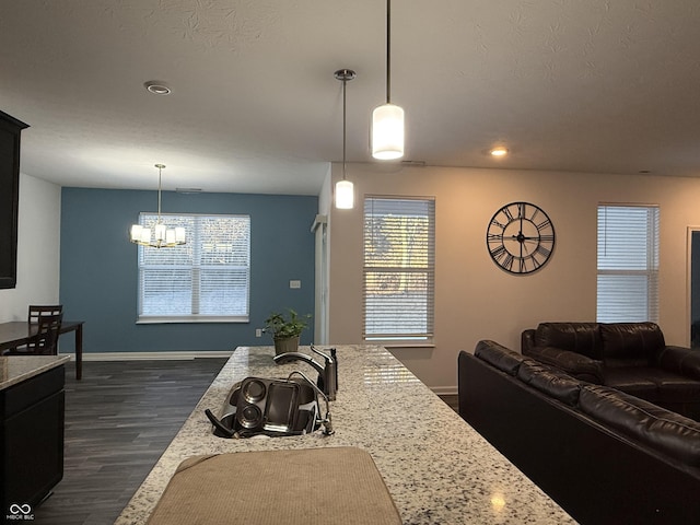 kitchen featuring hanging light fixtures, light stone counters, a notable chandelier, a textured ceiling, and dark hardwood / wood-style flooring