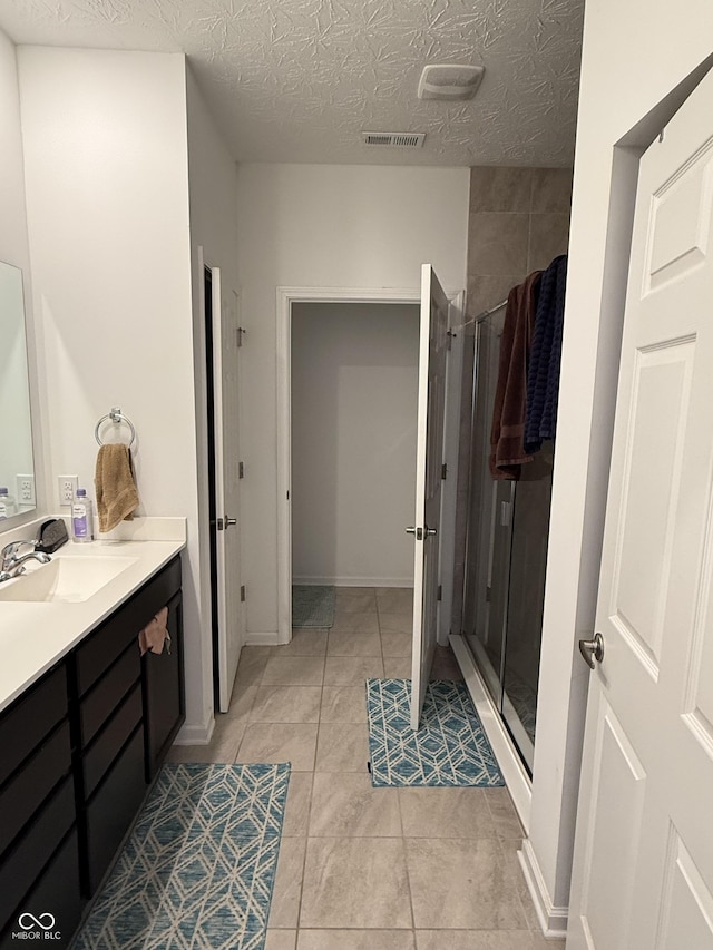 bathroom with vanity, tile patterned floors, a shower with door, and a textured ceiling