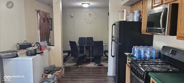 kitchen with washer / clothes dryer, gas stove, dark hardwood / wood-style floors, and a textured ceiling