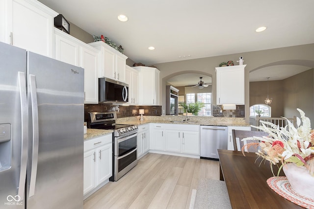 kitchen featuring white cabinetry, backsplash, stainless steel appliances, light stone countertops, and light hardwood / wood-style flooring