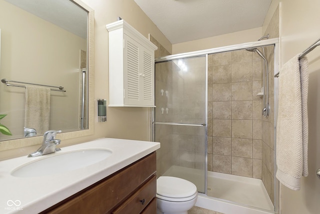 bathroom featuring walk in shower, vanity, toilet, and a textured ceiling