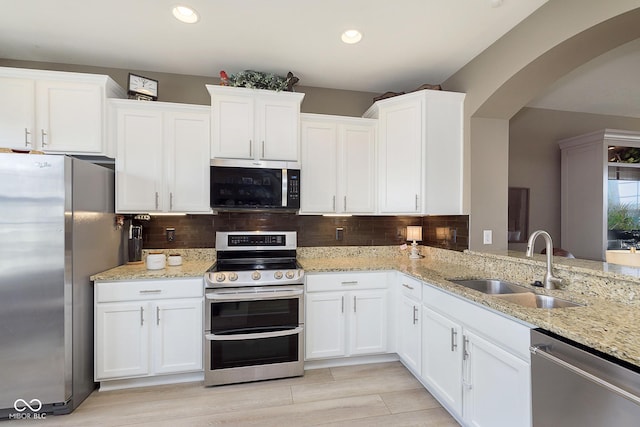 kitchen with sink, light stone countertops, white cabinets, and appliances with stainless steel finishes