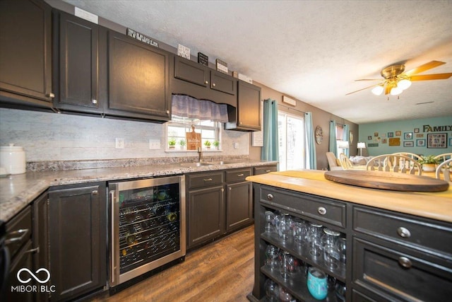 kitchen with dark hardwood / wood-style floors, wine cooler, decorative backsplash, dark brown cabinets, and a textured ceiling