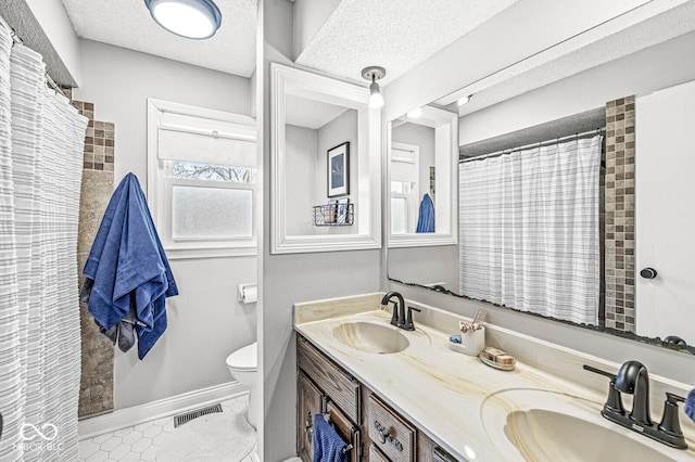 bathroom with tile patterned floors, vanity, toilet, and a textured ceiling