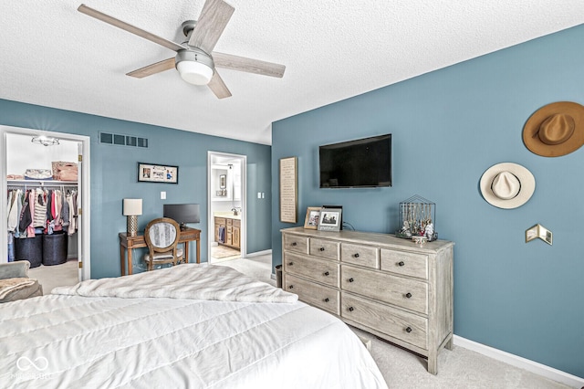 bedroom featuring a walk in closet, light colored carpet, ceiling fan, a textured ceiling, and a closet