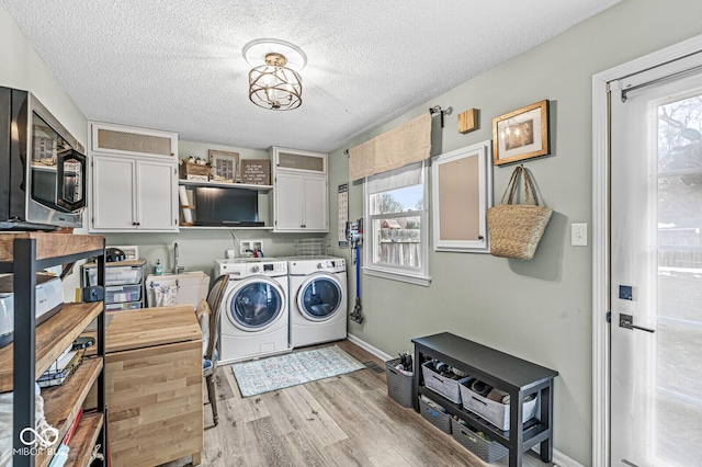 washroom featuring sink, cabinets, a textured ceiling, light wood-type flooring, and washing machine and dryer