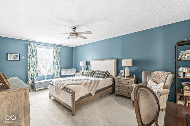 bedroom featuring a textured ceiling, light colored carpet, and ceiling fan