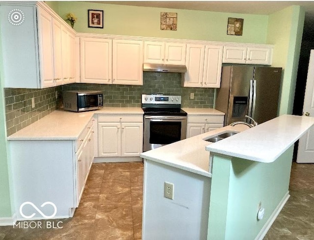 kitchen with appliances with stainless steel finishes, tasteful backsplash, white cabinetry, sink, and a center island